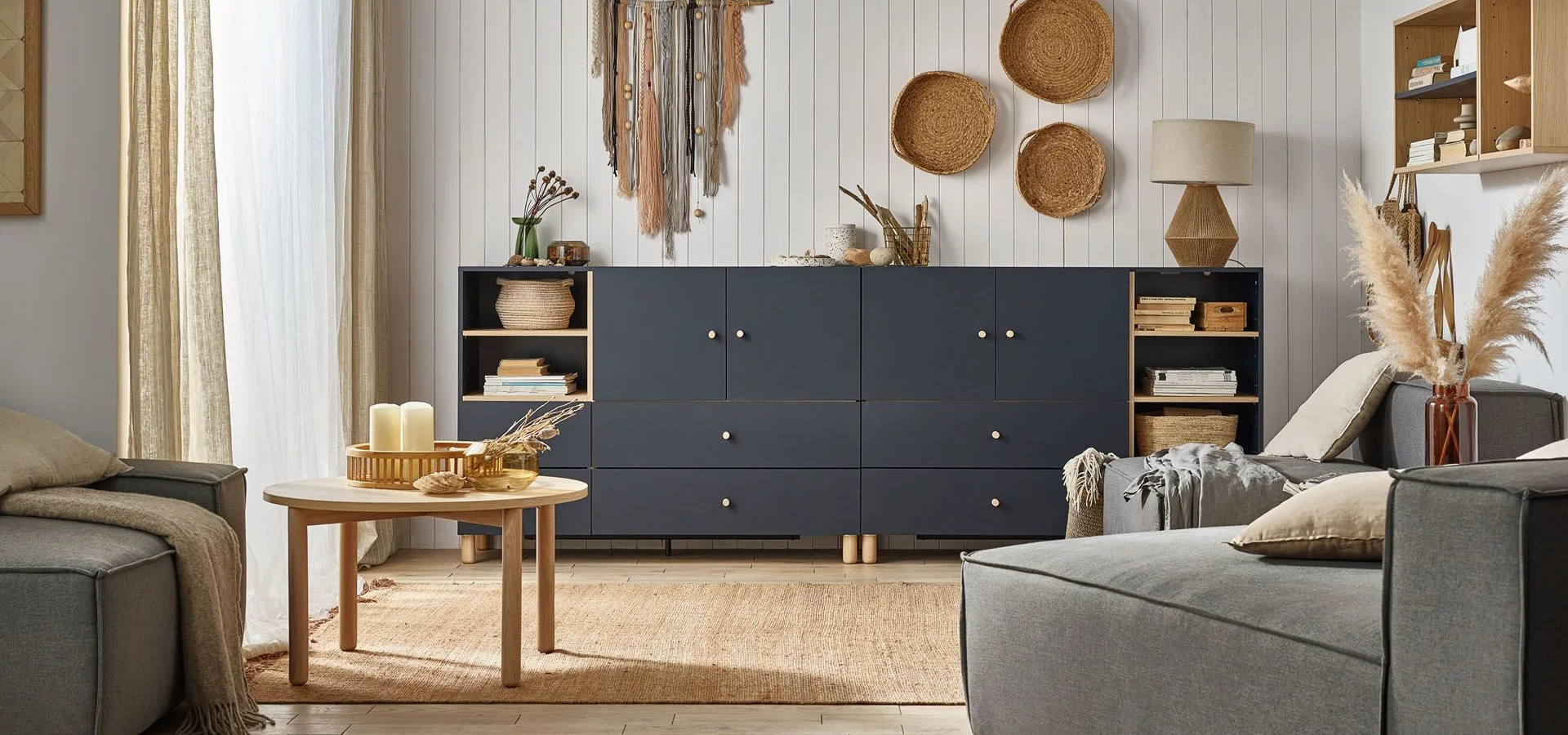 Salon z granatową komodą i naturalnymi dekoracjami w stylu boho.